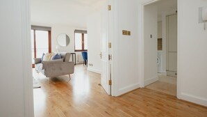 Un'ampia zona giorno con un divano grigio, uno specchio rotondo e vista all'esterno da una finestra.