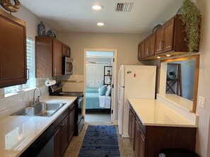 Compact kitchen with a stainless steel sink, microwave, and oven.