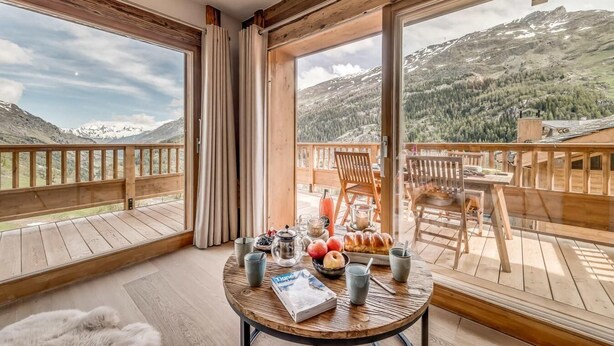 A wooden deck with a table set for breakfast, overlooking a mountainous landscape. - 50m from ski slopes, 5th floor, swimming pool, sauna, hammam, balcony, tv, ski locker, 93m², Tignes (Tignes)