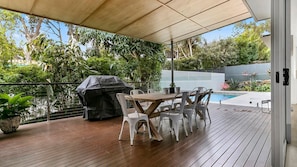 Enjoy al fresco dining and relaxation on the patio overlooking the pool, surrounded by lush greenery.
