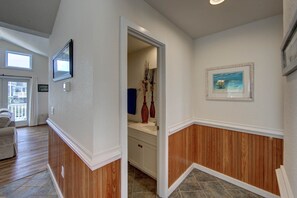 A hallway with wooden paneling, a white door leading to a bathroom, and a framed picture on the wall.