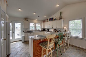 A spacious kitchen with white cabinets, a central island, and a dining area with chairs.
