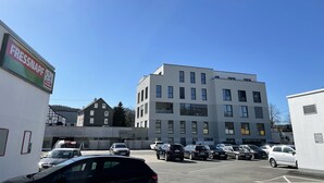 A parking lot with several cars, a modern building with multiple windows, and a sign for 'Fressnapf' on the left.