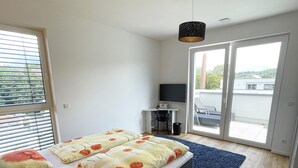 A bedroom with a bed, a desk, and a view through a sliding door.