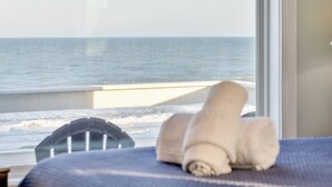 Une chambre avec vue sur la mer, un lit avec une serviette roulée et une fenêtre.