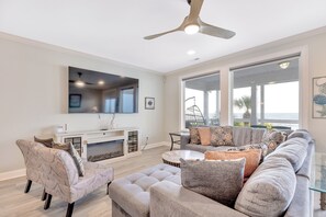 A modern living room with a sectional sofa, ottoman, and a flat-screen TV mounted on the wall. - Beach Cabana: Oceanfront + Private Pool (Surfside Beach)