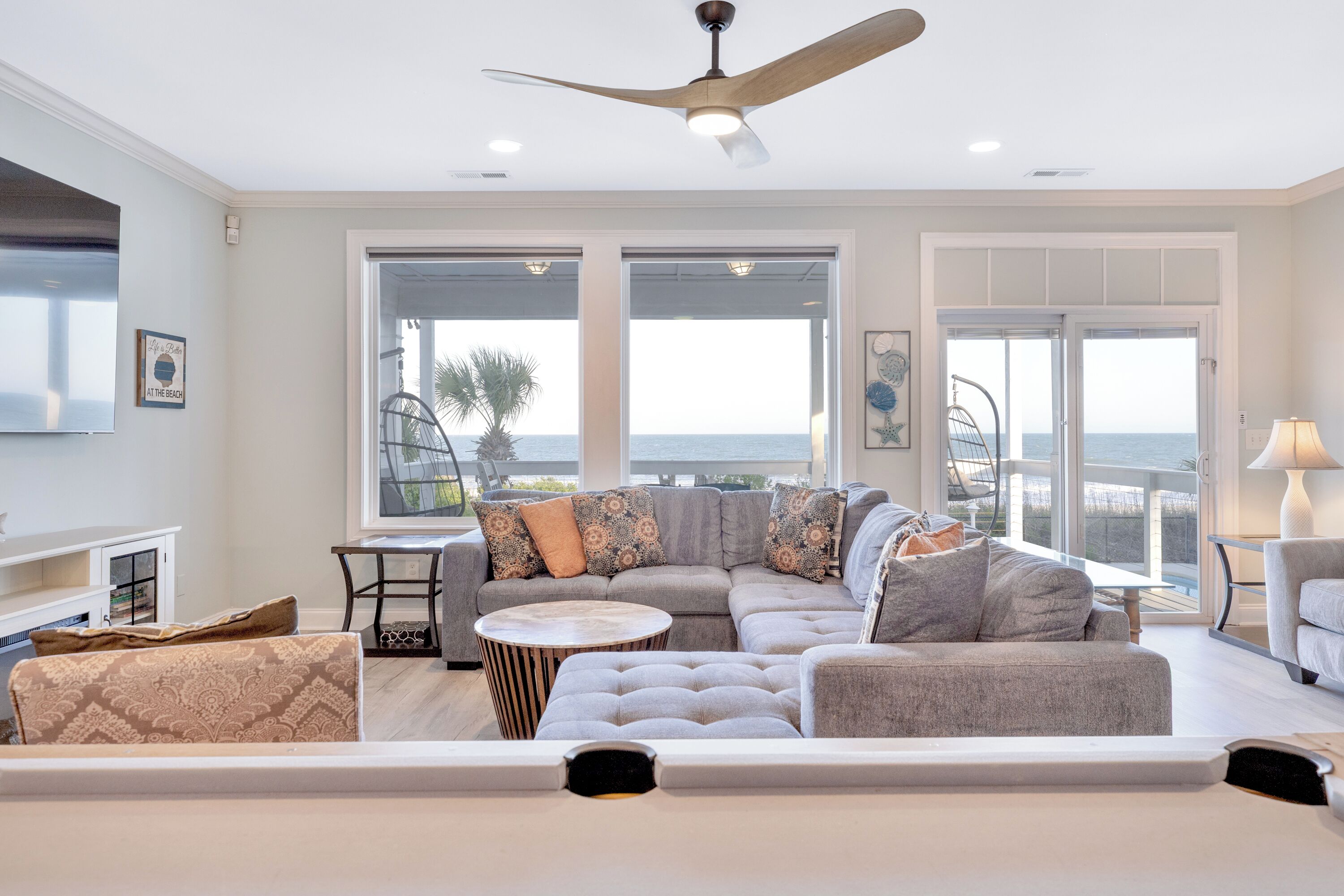 A modern living room with a sectional sofa, a round coffee table, and a ceiling fan.