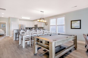 A pool table in a room with a dining area, kitchen, and large windows. - Beach Cabana: Oceanfront + Private Pool (Surfside Beach)