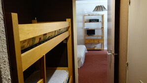 A bunk bed in a room with a carpeted floor and a door leading to a hallway with a shelf and a lamp. - Plagne Montalbert Studio 4 people (Montalbert)