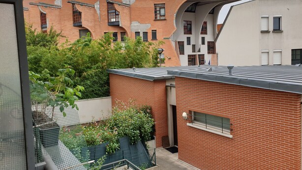 A modern building with a red brick facade, large windows, and a unique curved architectural feature. - Spacious apartment - Paris St Denis, stade de France (Saint-Denis)