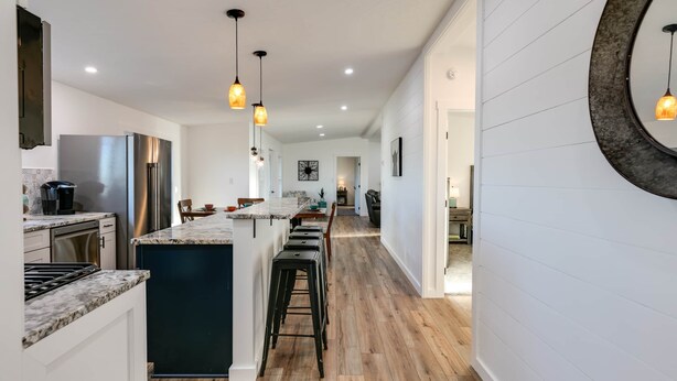 Una cocina moderna con una isla central, electrodomésticos de acero inoxidable e iluminación colgante.