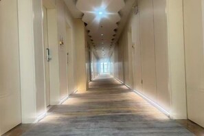 A long, narrow hallway with doors on both sides, leading to a bright end. - Bailandi Boutique Hotel (Kunshan)