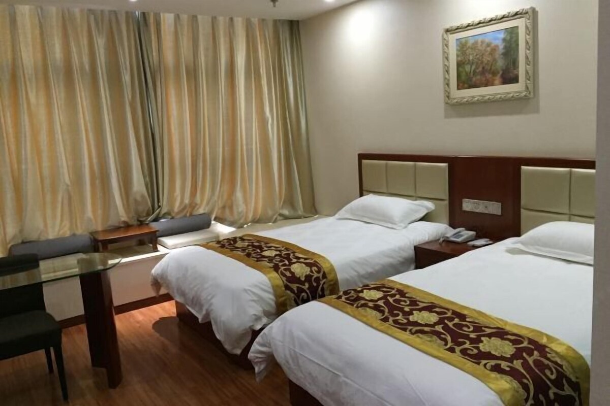 A hotel room with two beds, a desk, and a chair.