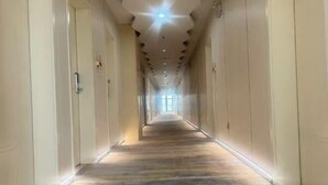Un long couloir étroit, doté d’un sol recouvert de moquette et d’un luminaire au plafond.