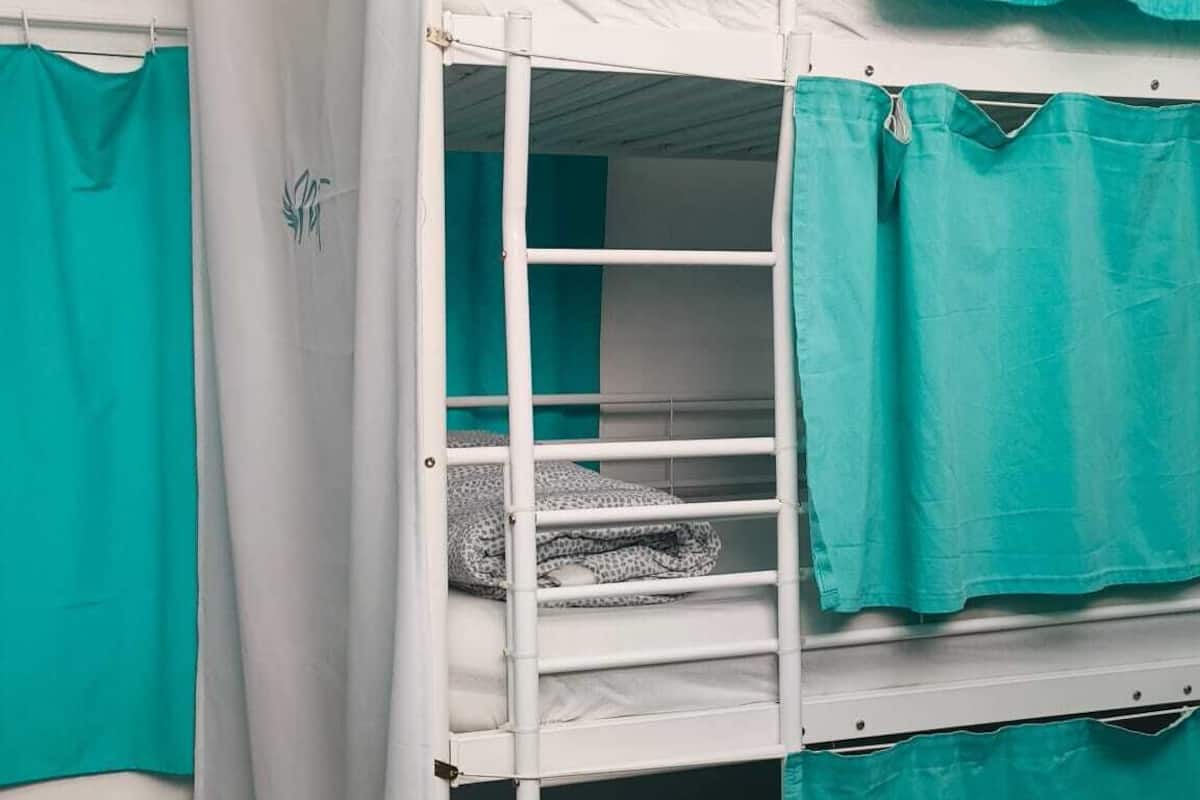 Una cama litera con cortinas color turquesa y un colchón blanco.