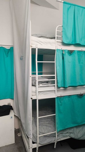 A bunk bed with teal curtains and a white mattress.