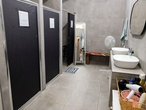 Un baño con dos lavamanos, un espejo, un ventilador y una zona de ducha.