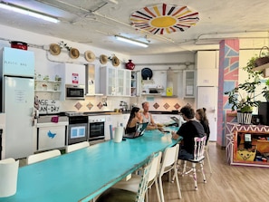 A kitchen with a turquoise countertop, white cabinets, and a variety of kitchen appliances. - Medano Nest Hostel (Granadilla de Abona)