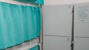 A room with a bed covered by teal sheets, a metal wardrobe with a lock, and a note on the door. - Medano Nest Hostel (Granadilla de Abona)