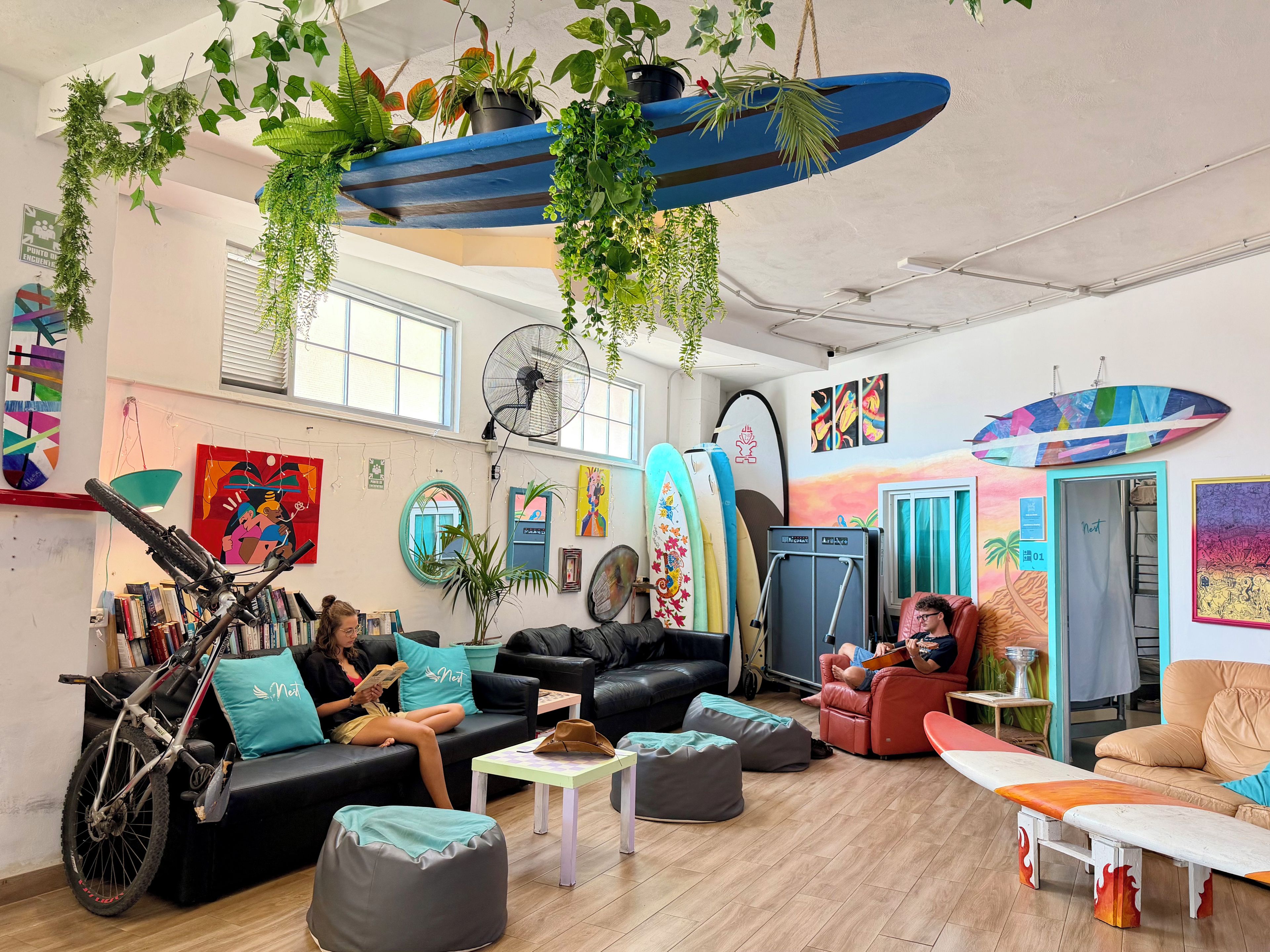 Una sala de estar moderna con una bicicleta, varias zonas de estar y tablas de surf.