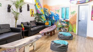 A cozy room with a sofa, a bench, bean bags, a guitar, and a bookshelf.