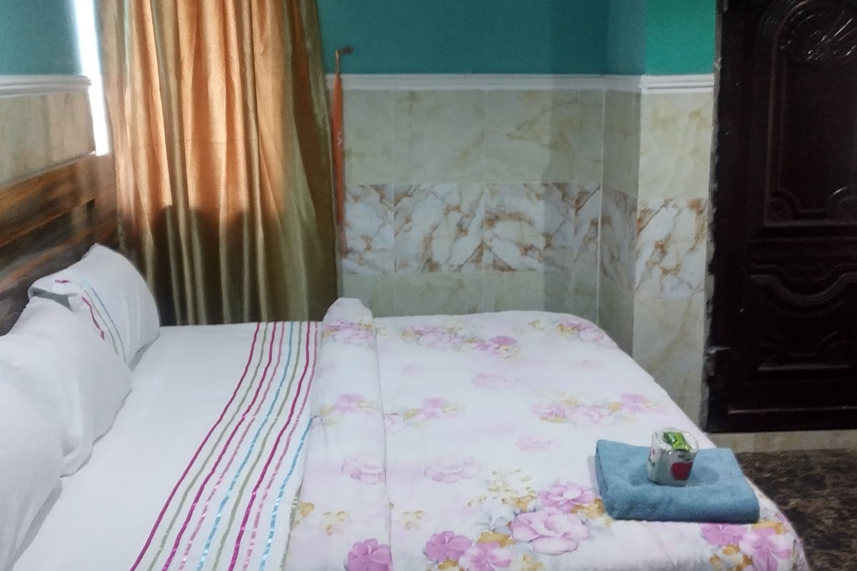 A bed with a floral bedspread, a striped pillow, and a blue towel on the footboard.