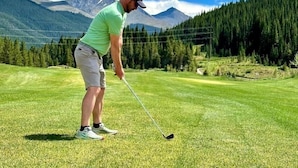 Una persona en un campo de golf, con montañas al fondo.