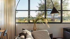 Una sala moderna con un ventanal grande, una planta en maceta y un sofá.