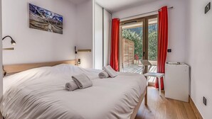 Une chambre à coucher avec un lit, un bureau, une chaise, un radiateur et une fenêtre avec des rideaux rouges.