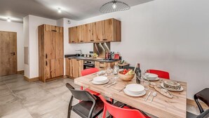 Une cuisine moderne avec des meubles en bois, un four encastré et un coin repas comprenant une table en bois et des chaises rouges.