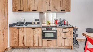 Une cuisine moderne avec des meubles en bois, un évier en acier inoxydable, un four et une machine à café.