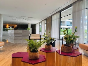 Relax in our spacious lobby with a central seating area, surrounded by lush greenery and natural light pouring in through large windows.