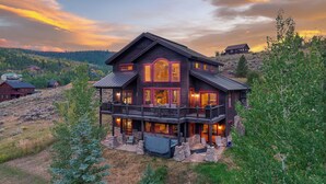 Ein großes, mehrstöckiges Haus mit Balkon, umgeben von Bäumen und einer hügeligen Landschaft.