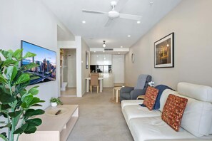 Una sala moderna con un sofá, una mesa de centro, un televisor y una planta.