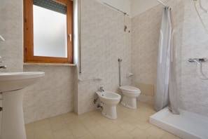 A bathroom with a sink, two toilets, a shower, and a window with a wooden frame. - 2242 Residence Anna - Appartamento Salmone (Taviano)