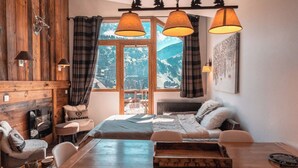 A cozy room with a wooden wall, a bed, a dining table, and a view of mountains. - Immodreams - La Marmotte - Avoriaz (Avoriaz)