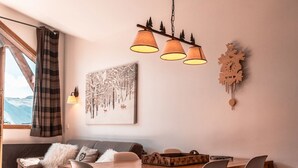 A cozy living room with a wooden dining table, four chairs, a sofa, a fireplace, and a large window with a view of mountains. - Immodreams - La Marmotte - Avoriaz (Avoriaz)