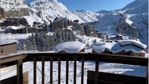 A snow-covered mountain town with buildings, including a hotel named AQUARIATZ, and a wooden deck in the foreground. - Immodreams - La Marmotte - Avoriaz (Avoriaz)