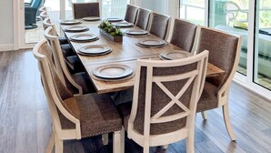 Comedor con una larga mesa dispuesta para seis personas, rodeada de sillas tapizadas.
