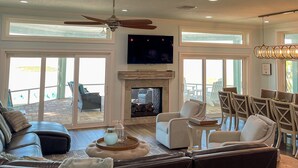 Un salón espacioso con chimenea, asientos cómodos y grandes ventanales que ofrecen vistas al exterior.