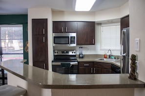 Enjoy cooking in this well-equipped kitchen with a window, microwave, oven, and refrigerator.