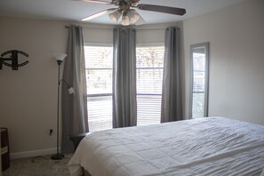 Relax in this serene bedroom with a large bed, flanked by two windows and a ceiling fan.