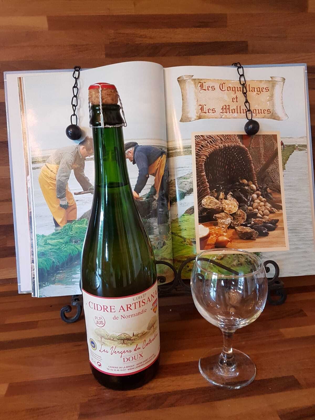 Un livre ouvert, une bouteille de vin et un verre à vin, le tout posé sur une surface en bois.