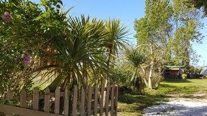 A gravel path leading to a wooden fence with lush greenery and a small structure in the background. - Charming cottage "La Casa Céline", near the sea (Surtainville)