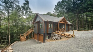 Uma cabana com base de pedra, deck de madeira e escadas que levam à entrada.