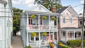 A two-story house with a balcony, a front porch, and a small garden area. - The Isla Suite: A Dream Getaway for Friends (Charleston)