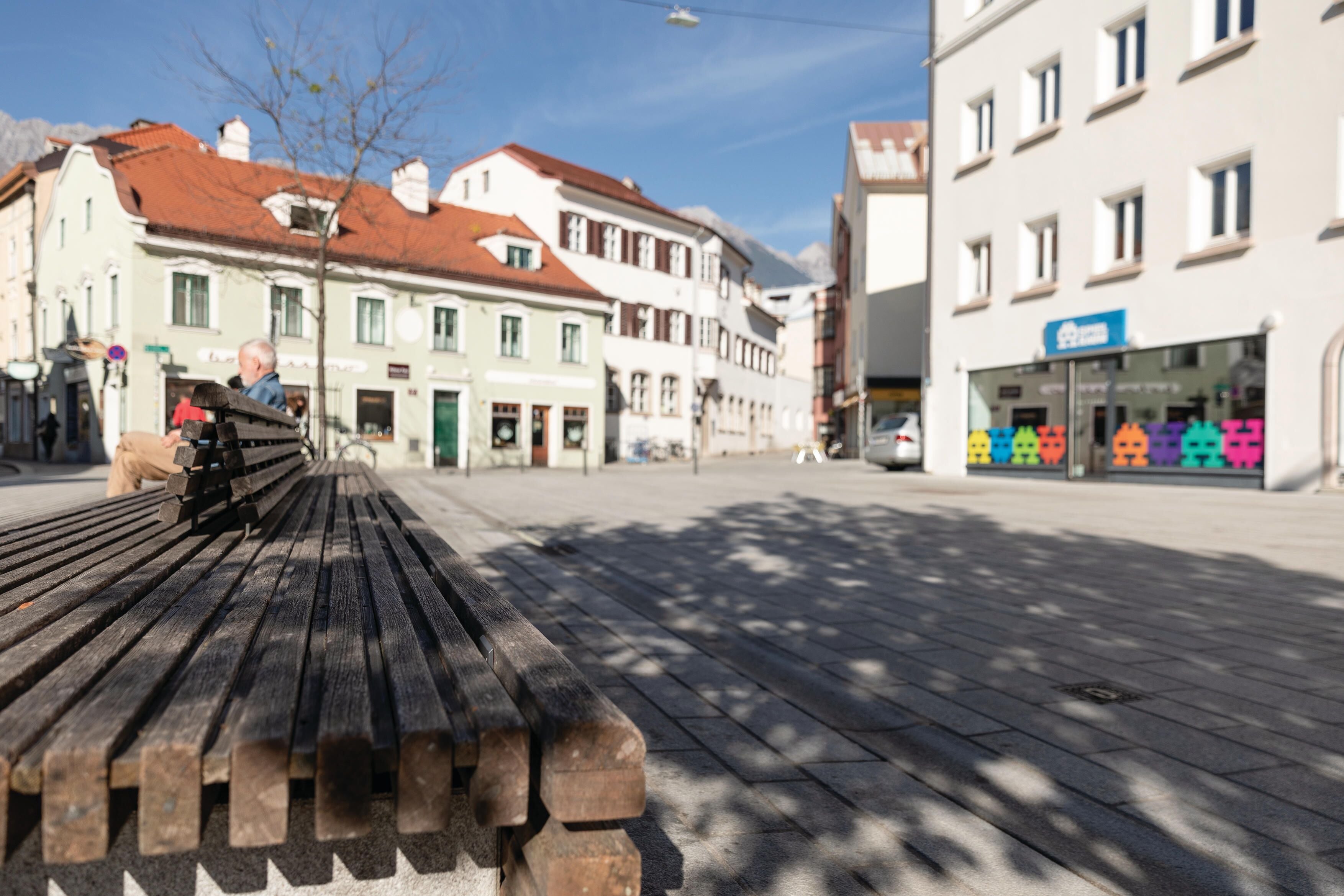 A bench in a public square with buildings in the background.