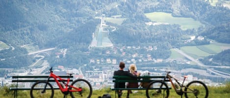 A couple sitting on a bench overlooking a valley with bicycles nearby.