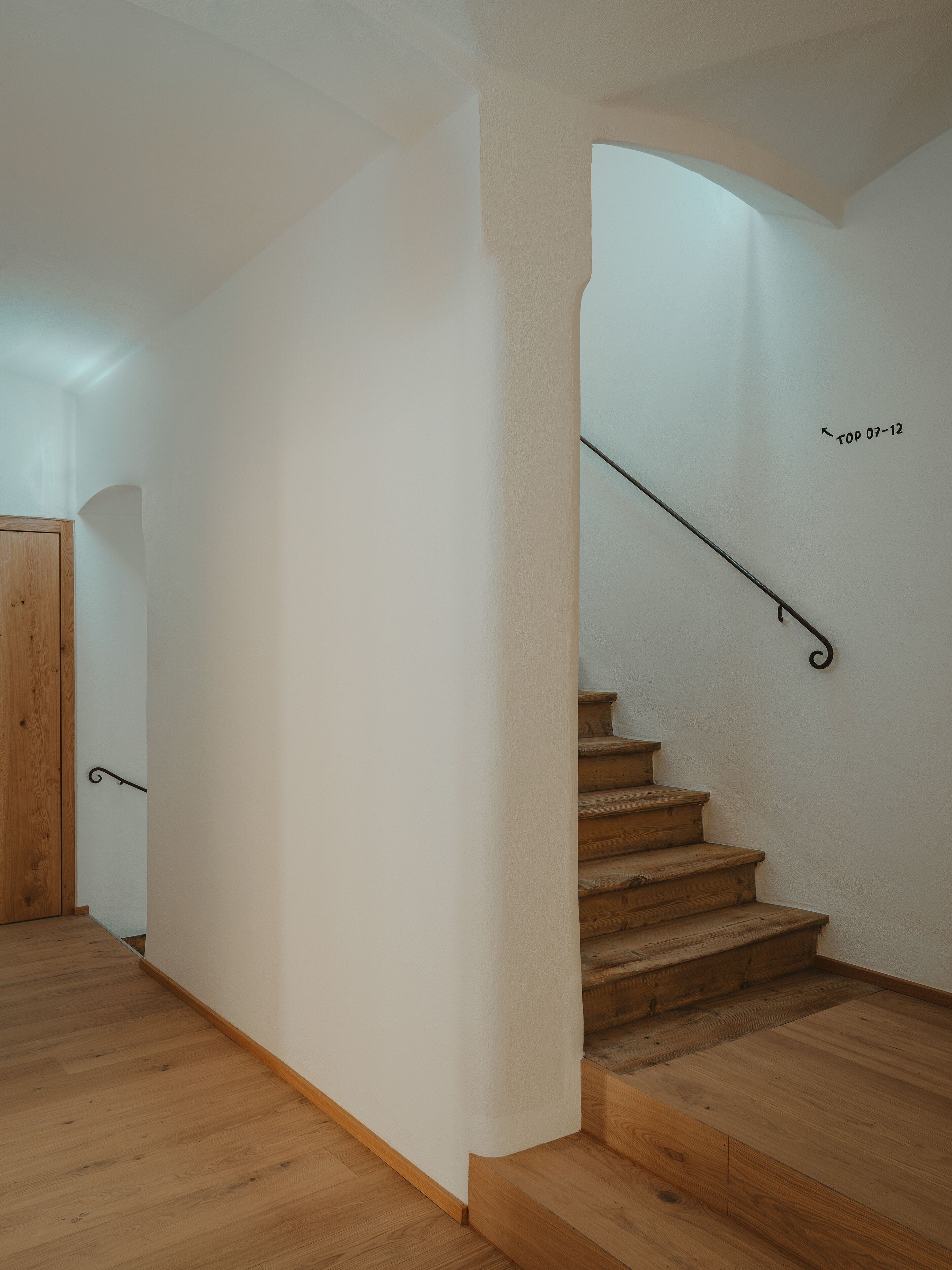 A wooden staircase with a metal handrail leading to a landing.