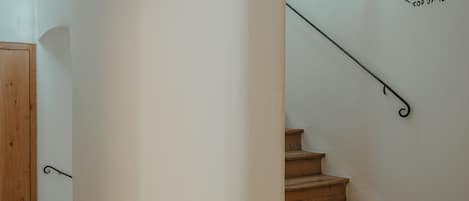 A wooden staircase with a metal handrail leading to a landing.